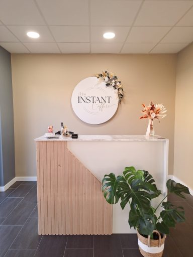 Réception moderne avec un comptoir et un panneau "INSTANT", décoré de plantes et fleurs.